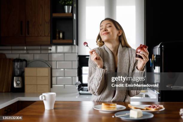 retrato de joven feliz comiendo mermelada en la cocina - sabor fotografías e imágenes de stock