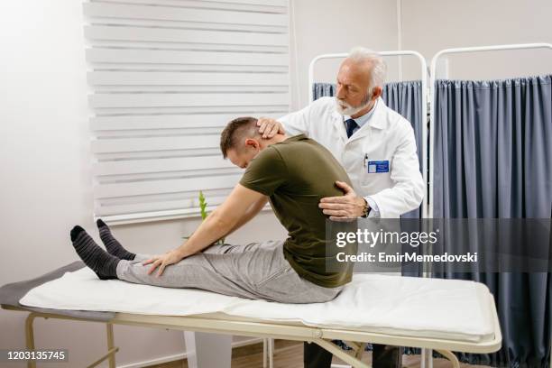 male doctor therapist treating patient lower back pain in clinic - lower back stock pictures, royalty-free photos & images