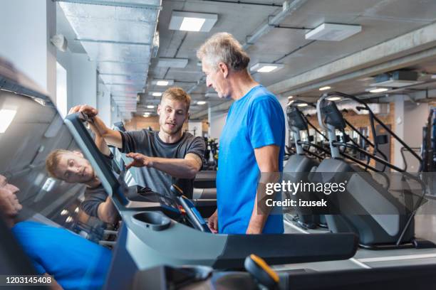 fitness instructor explaining training plan for senior in gym - leisure facilities stock pictures, royalty-free photos & images