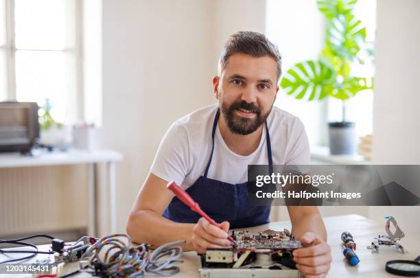 mature man repairing household equipment in community center. - repair shop foto e immagini stock