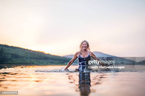 active senior woman standing in water in lake outdoors in nature. copy space. - frau sommer natur bewegung freude sport stock-fotos und bilder