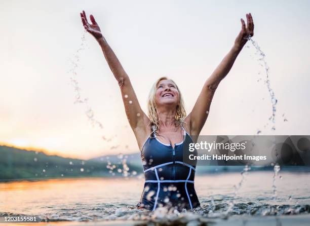 active senior woman standing in water in lake outdoors in nature. copy space. - frau sommer natur bewegung freude sport stock-fotos und bilder