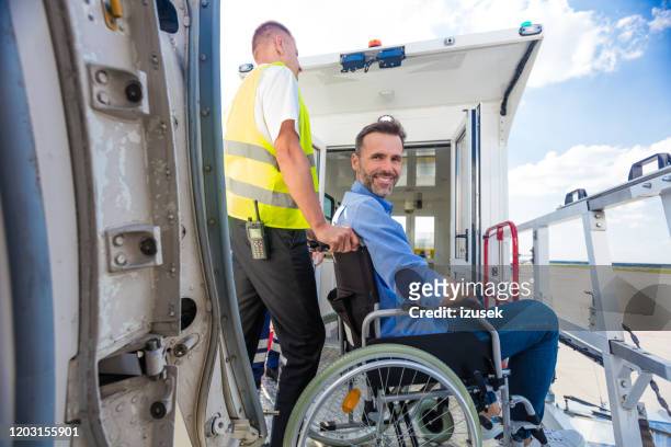 service man helping disabled passenger to enter on board at airport - medical transportation stock pictures, royalty-free photos & images