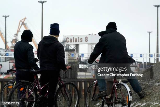 Migrants observe ferries arriving and leaving the Calais Ferry terminal on January 31, 2020 in Calais, France. At 11.00pm on Friday 31st January the...