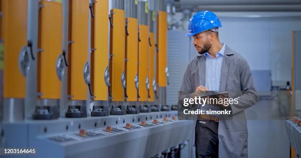 mannelijke ingenieur die digitale tablet in fabriek gebruikt - manufacturing machinery stockfoto's en -beelden