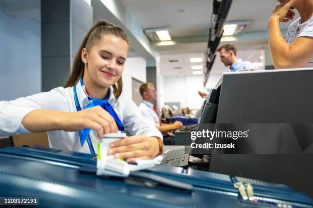 luchtvaartmaatschappij chech-in bediende die markering op bagage bevestigt - airport staff stockfoto's en -beelden