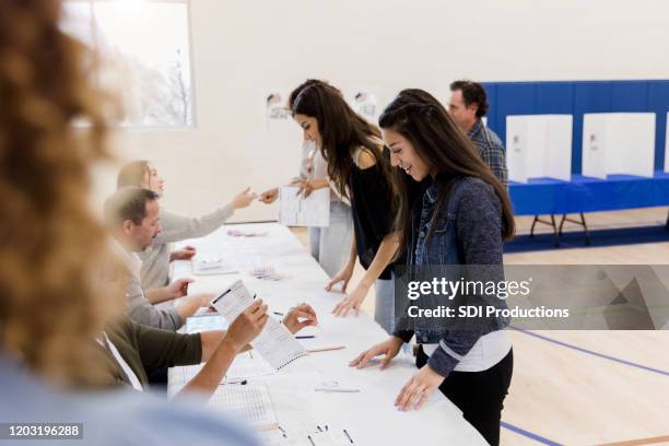 de vrouwen bevinden zich in rij terwijl het ondertekenen omhoog om te stemmen - young voters stockfoto's en -beelden