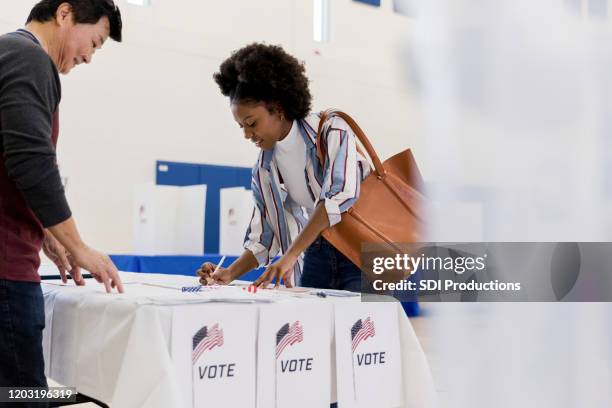 de jonge vrouw schrijft omhoog aan om als vrijwilligerhorloges te stemmen - polling place stockfoto's en -beelden