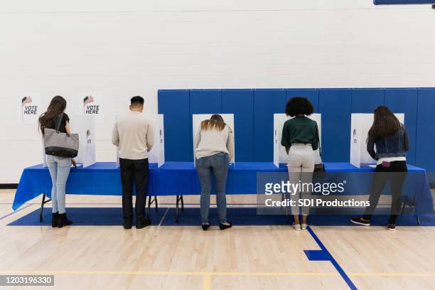 rear view photo five people casting ballots - local de votação imagens e fotografias de stock