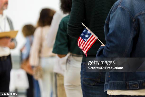 diverse group in line to vote; one holds american flag - election stock pictures, royalty-free photos & images