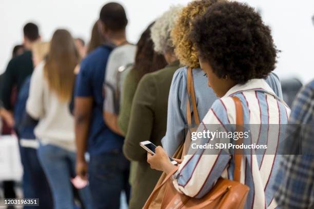 vista trasera foto de la línea de personas que esperan votar - hacer cola fotografías e imágenes de stock
