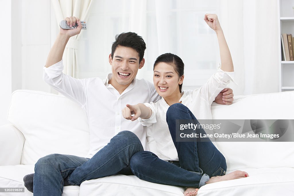 Happy young couple watching TV together