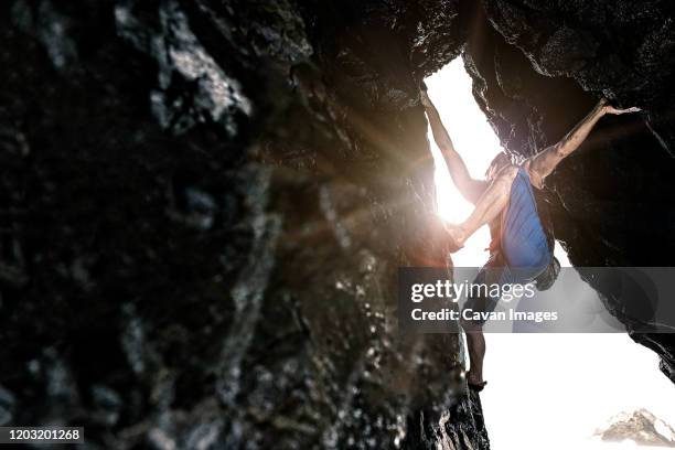 male bouldering with sun flare  in background - spelunking ストックフォトと画像