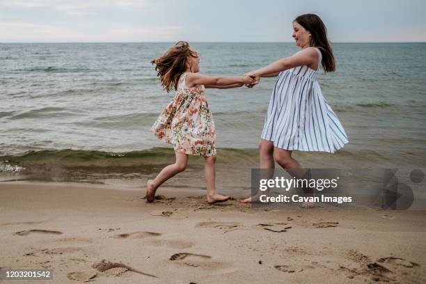 girls spinning and playing on beach along lake michigan - holland michigan stock pictures, royalty-free photos & images