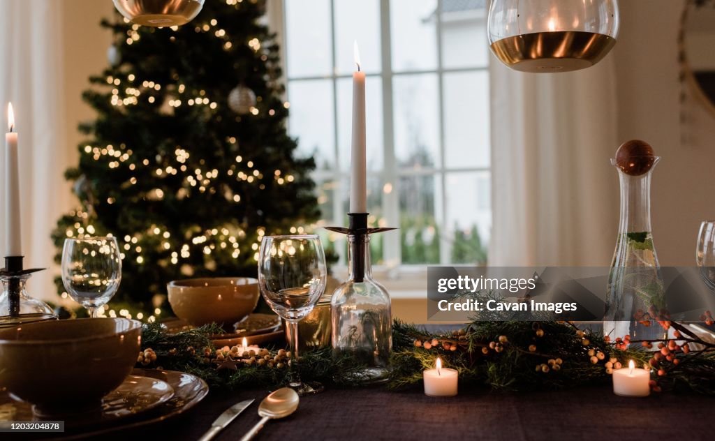 Tall candle on a festively decorated dinner table at Christmas