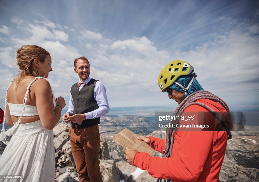 Climbing guide with helmet reads vows during mountaintop wedding