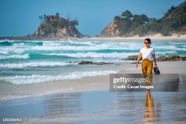 woman walking barefoot on the beach in byron bay / australia - byron bay stock-fotos und bilder
