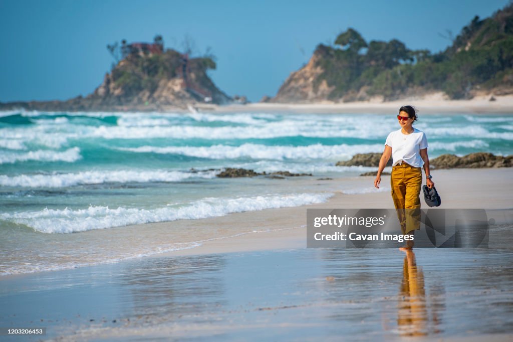 Woman walking barefoot on the beach in Byron Bay / Australia