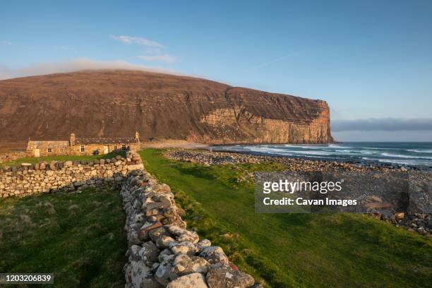 burnmouth bothy stone shelter in below dramatic sea cliffs at rackwick bay, hoy, orkney, scotland - orkney stock pictures, royalty-free photos & images