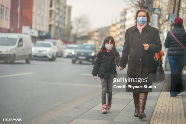vrouw gaat werken.ze draagt n95 masker.voorkomen pm2.5 stof en smog, moeder en kind draagt een masker om hun kind te beschermen tegen luchtvervuiling en infectieziekten - air pollution mask stockfoto's en -beelden