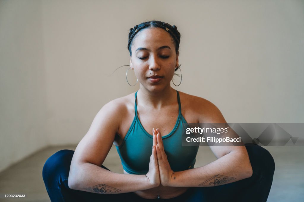 Young adult woman practicing yoga in garland position