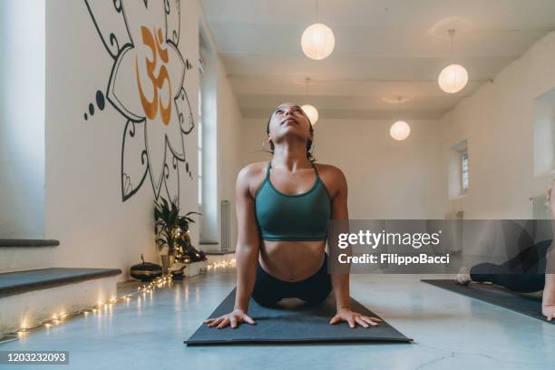 joven mujer adulta practicando yoga en el estudio de yoga haciendo pose de saludo al sol - yoga caliente fotografías e imágenes de stock