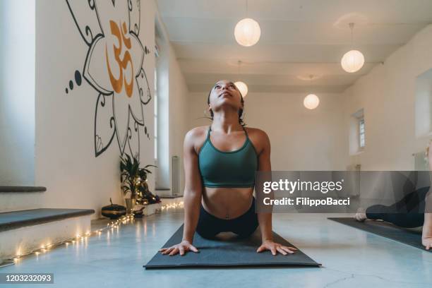 young adult woman practicing yoga at the yoga studio doing sun salutation pose - hot yoga stock pictures, royalty-free photos & images