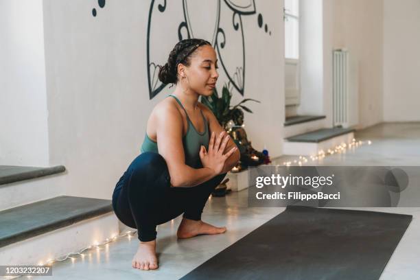 mujer adulta joven practicando yoga en posición de guirnalda - yogi fotografías e imágenes de stock