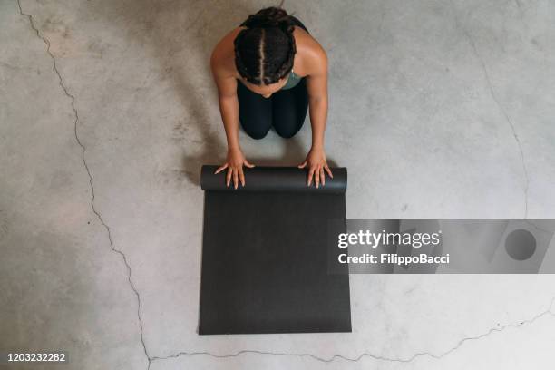 high angle view of a young adult woman closing a yoga mat - rolling stock pictures, royalty-free photos & images