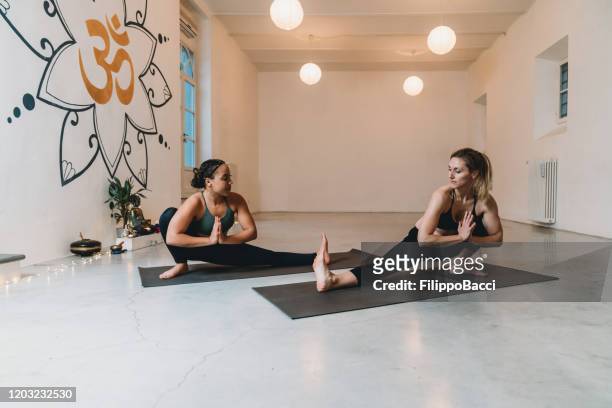 two women are practicing yoga together - yoga instructor stock pictures, royalty-free photos & images