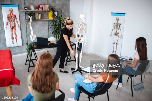 vrouwelijke leraar die alles over menselijk lichaam op plastic skelet bij anatomieklasse verklaart - course de skeleton stockfoto's en -beelden