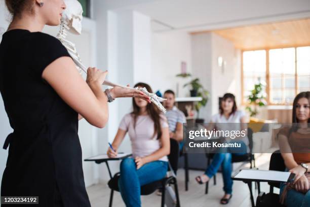 leraar die menselijke anatomie op plastic skelet verklaart - course de skeleton stockfoto's en -beelden