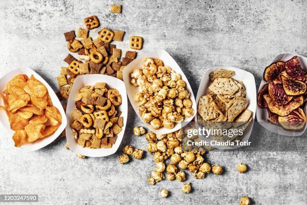 paper trays with caramelized popcorn, chips, and snack mix on gray background - salty snack stock pictures, royalty-free photos & images