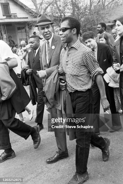 American author and activist James Baldwin smiles as he walks with unidentified others during the third Selma to Montgomery march, late March 1965.