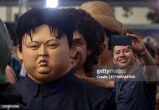 Man poses for a selfie next to giant puppet representing North Korea's leader Kim Jong-un during a traditional carnival parade through the streets of...