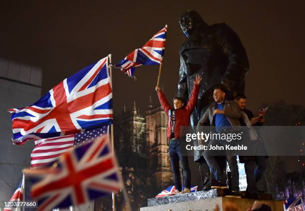 Pro Brexit supporters wave flags as they stand on the Winston Churchill statue during the Leave Means Leave, Brexit day celebration party outside the...