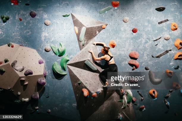 muscular woman on boulder climbing training - bouldern indoor stock pictures, royalty-free photos & images