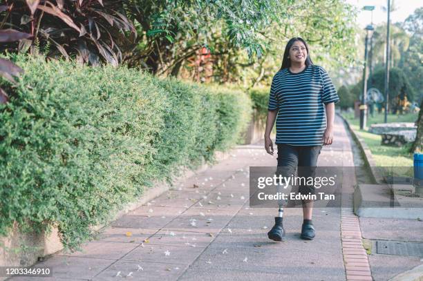 eine asiatische indische behinderte mit prothesen bein sport frau joggen in der öffentlichen park morgen sitzung - amputee stock-fotos und bilder