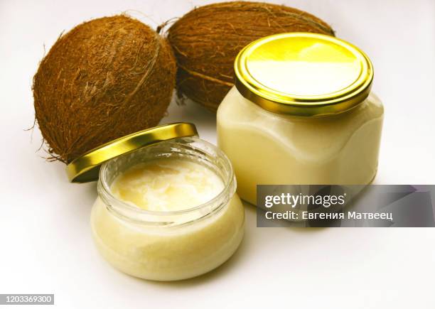 solid homemade coconut oil in glass jar with metal gold lid and fresh coconuts on a white background - fat massage stock pictures, royalty-free photos & images