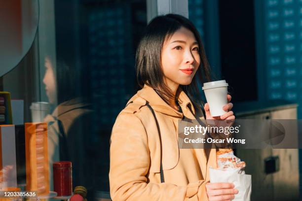 young businesswoman having coffee and croissant on the street - coffe to go stockfoto's en -beelden