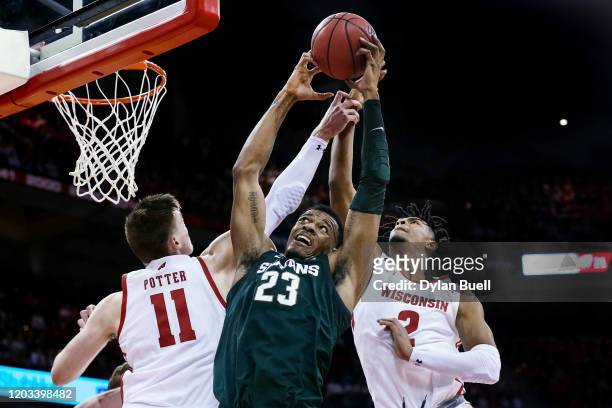 Xavier Tillman of the Michigan State Spartans grabs a rebound between Micah Potter and Aleem Ford of the Wisconsin Badgers in the first half at the...