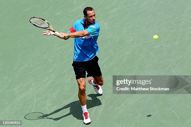 Michael Llodra of France returns a shot to Grigor Dimitrov of Bulgaria during the Legg Mason Tennis Classic presented by Geico at the William H.G....