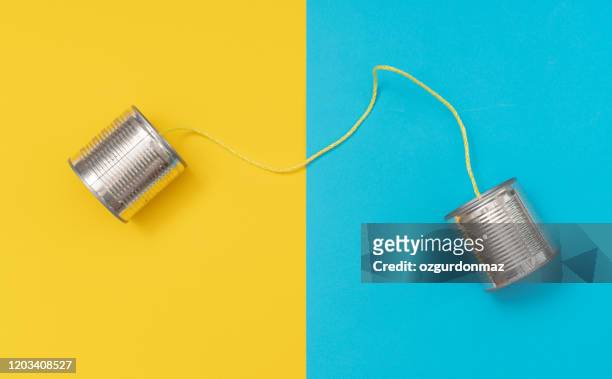 tin can phone on yellow and blue paper backgrounds - communication stock pictures, royalty-free photos & images