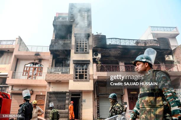 Security personnel patrol past burnt-out and damaged residential premises following clashes between people supporting and opposing a contentious...