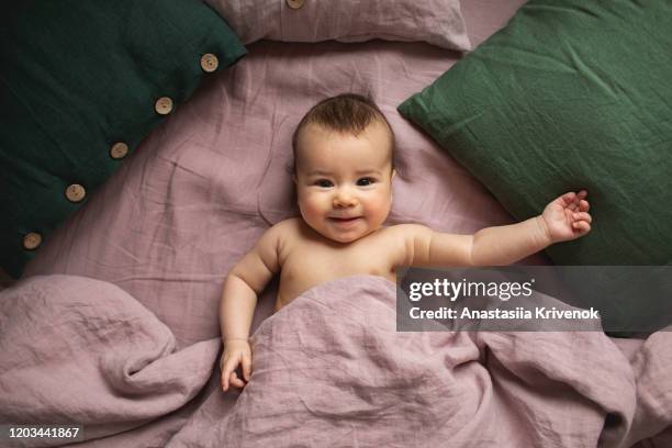 cute baby girl awake among pink and green pillows. - chambre bébé photos et images de collection