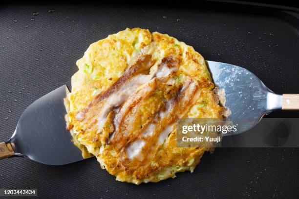 日本奧科諾米亞基食譜。岡野宮一在熱盤上烤。用鏟子翻過來。 - okonomiyaki 個照片及圖片檔