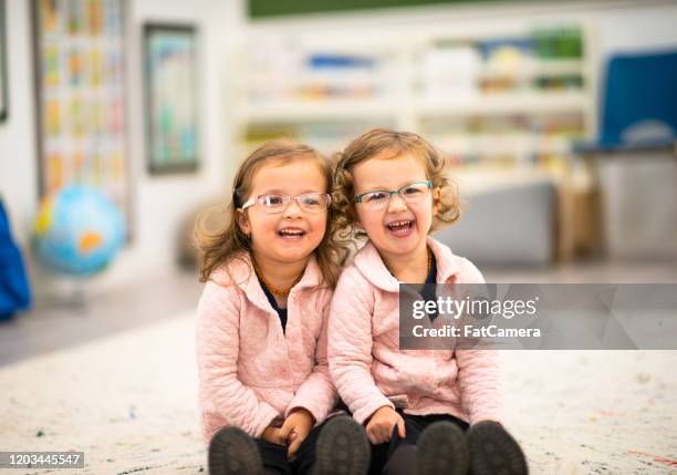 twin sisters in preschool stock photo - monocles stock pictures, royalty-free photos & images