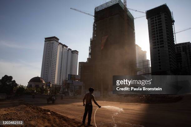Man washes down a dirt road to control the dust in Sihanoukville, Cambodia on February 16, 2020. Chinese are permanently changing the quiet oceanside...