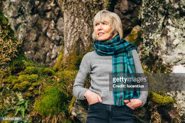 woman wearing tartan scarf in natural environment - plaid scarf stock pictures, royalty-free photos & images