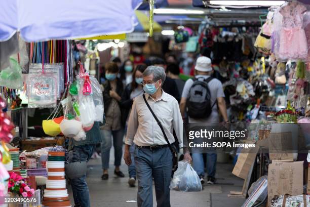 Masked senior walking through a market. Financial Secretary Paul Chan announced that the government spending forecast is to exceed revenue by HK$139...